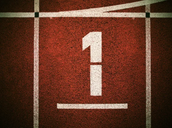 Number one. White track number on red rubber racetrack, texture of running racetracks in small outdoor stadium