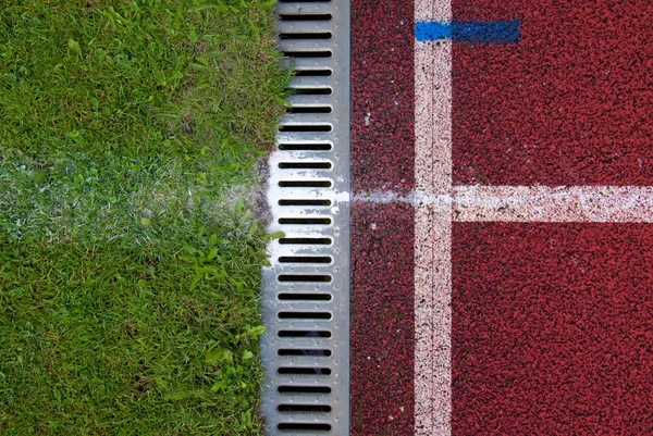 Channel at red running racetrack on the athletic stadium. Drain