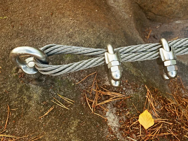 Mountain wall with hanger in the sandstone rock. End of the steel rope in loop.