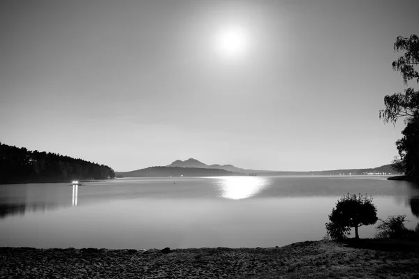 Romantic full moon night at lake, calm water level with moon rays. Burh on the hill.