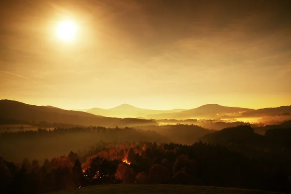 Ful moon night. The fog is moving between hills and peaks of trees a makes with rays gentle reflections. Wonderful autumn night