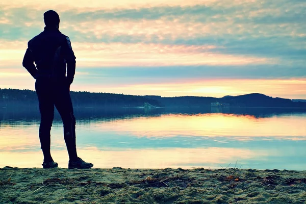 Silhouette of alone person on  decline seeing over bay to sun