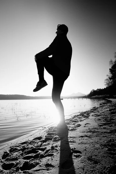 Silhouette of sport active man running and exercising on the beach at sunset.