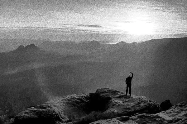 Black and white dashed retro sketch. Man stands on the peak of rock watch to Sun. Beautiful moment the miracle of nature