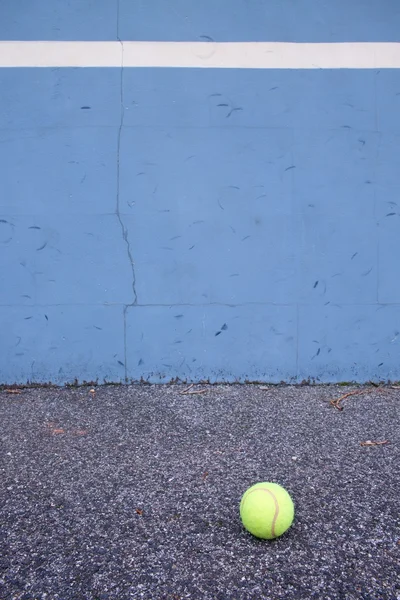 Ball beside tennis training wall. Empty training tennis court