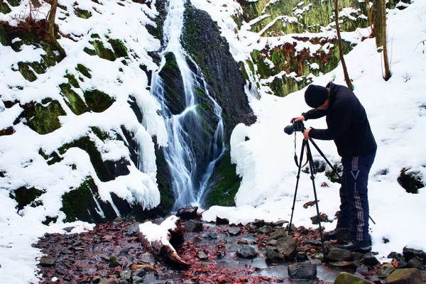 Professional photograph takes with camera on tripod  photo of winter waterfall.