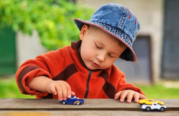 Little boy plays with colorful toy cars.
