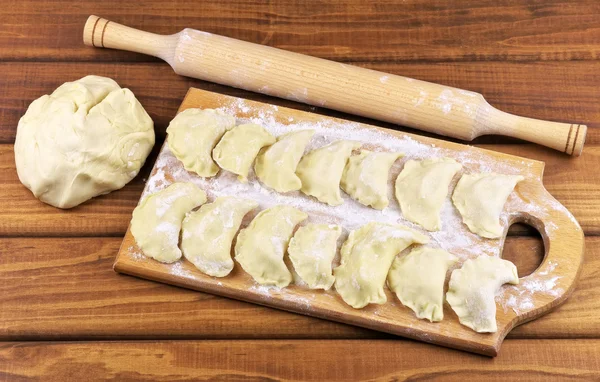 Vareniki with potatoes on a cutting board before cooking.