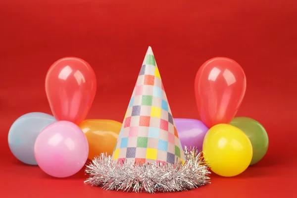 Party hat and party balloons on red background