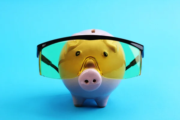 Pink piggy bank with yellow glasses on blue background like scientist