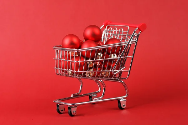 Full shopping basket of red matt and glossy christmas balls on red background