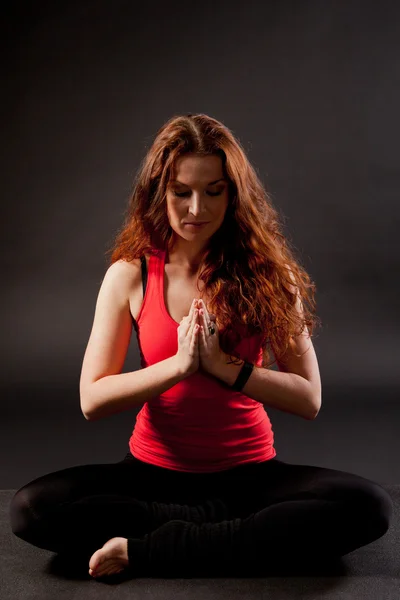 Young woman doing yoga on a black background