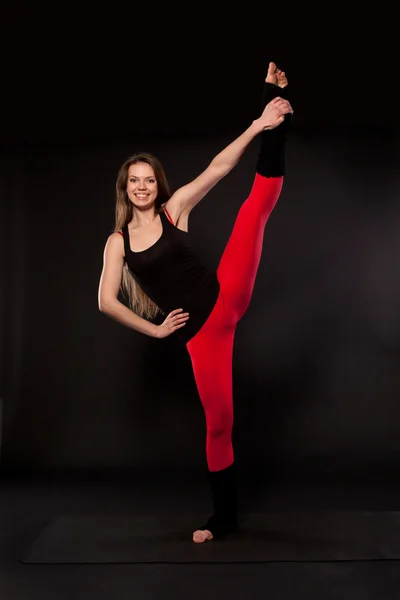 Young woman doing yoga on a black background