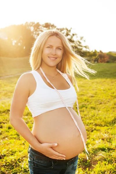 Portrait of pregnant woman with measuring tape