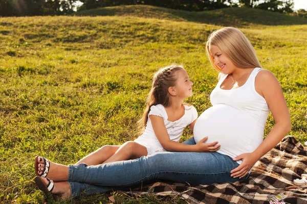 Happy little girl hugging her mother's pregnant belly