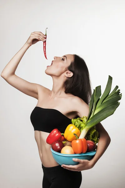 Portrait of young fit woman holding vegetables