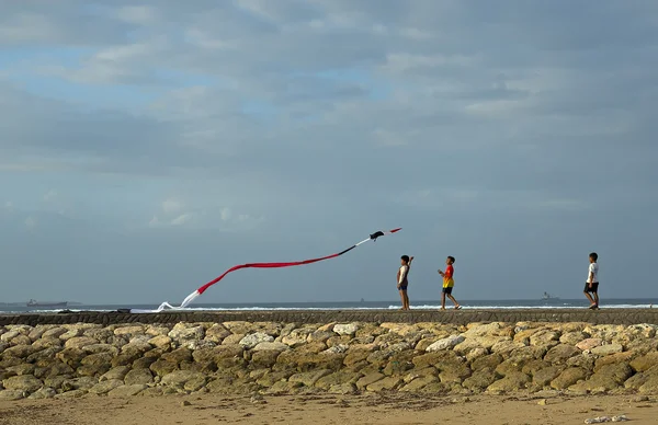 People try to fly a kite on a windy day at the Nusa Dua Beach