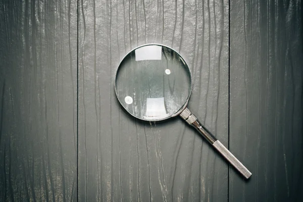 Close up Single Magnifying Glass with Handle on the Wooden Table