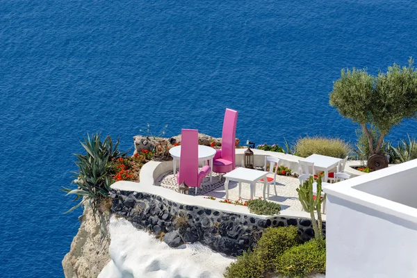 Two purple chairs on balcony of Santorini  island cliff