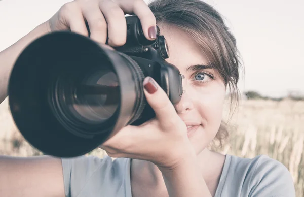 Photo face of a young woman with photographic equipment in the field working for her pleasure