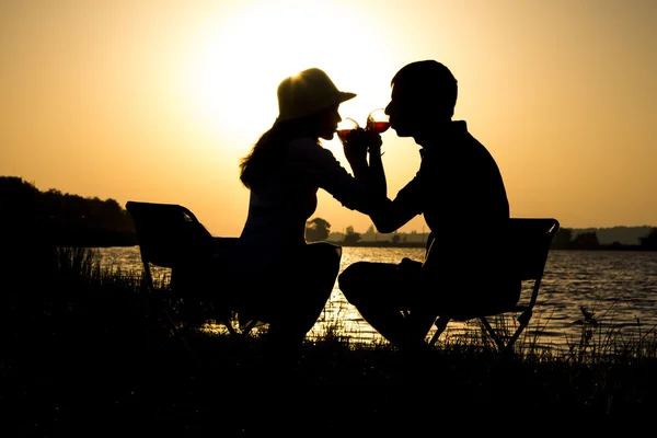Silhouette of a young couple in love to leave on a picnic out of town at dawn drinking wine brotherhood