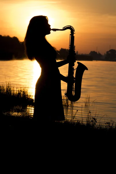 Girl on the dawn on the banks of the river who found joy in his hobby - music
