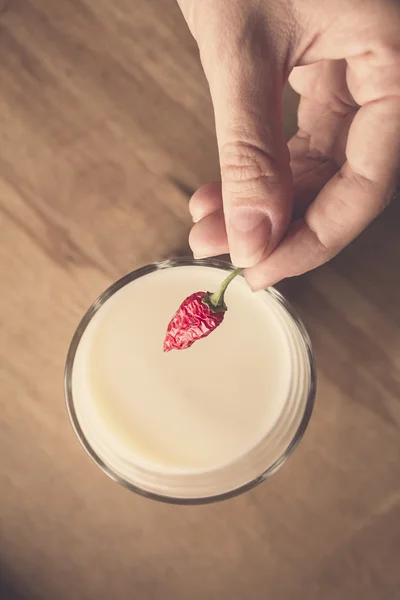 Woman who puts it in a small glass of milk dried bitter pepper to taste