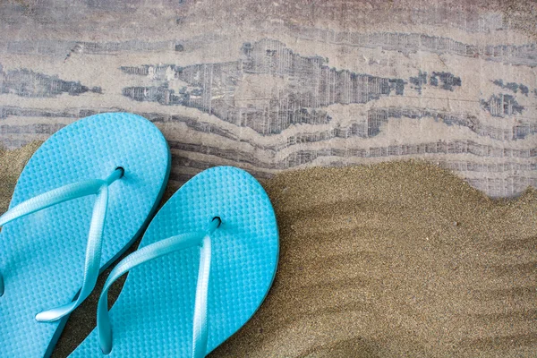 Summer shoes on sand and wooden background