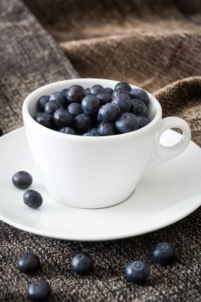 Blueberries in a cup on a brown cloth