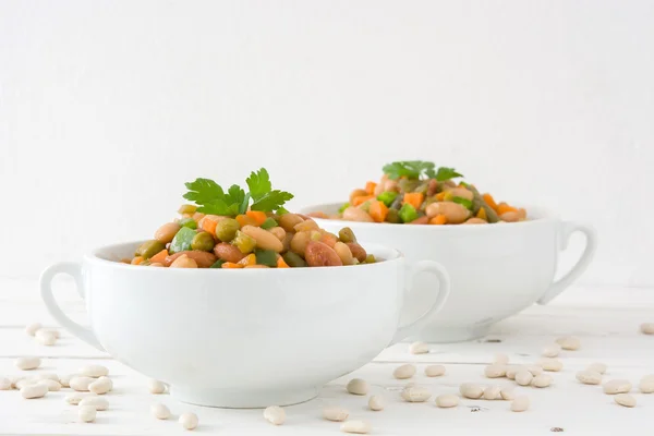 White beans with vegetables on white wood