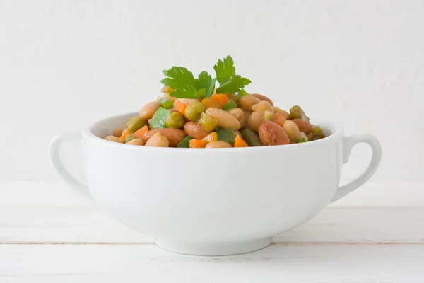 White beans with vegetables on white wood