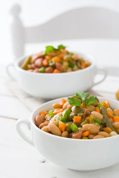White beans with vegetables on white wooden table
