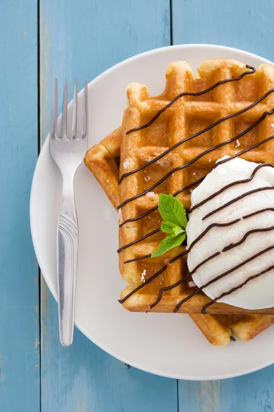 Waffles with ice cream on blue wood