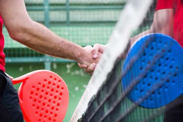 Friends shaking hands in paddle tennis field
