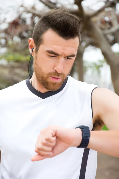 Man doing running and watching the watch in park