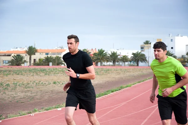 Two men running on running track