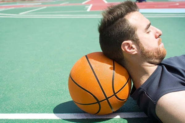 Man lying on the floor of a basketball field