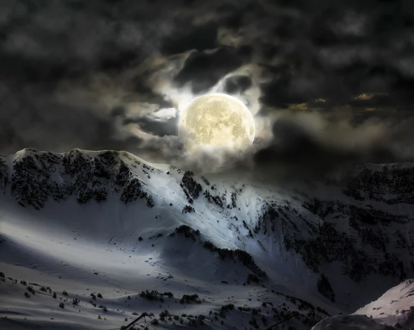 The full moon in the sky over the mountain snow peak