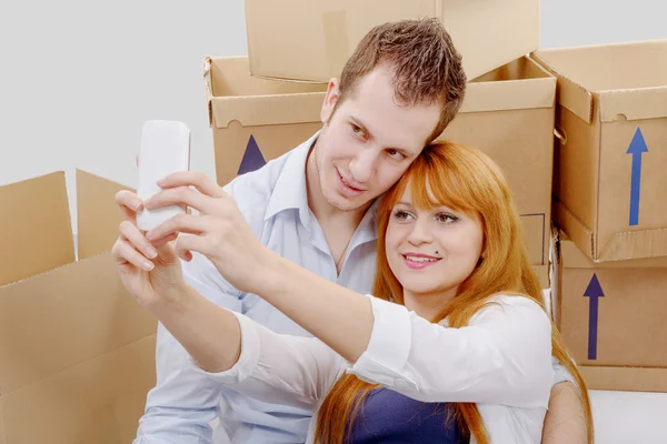 Happy couple sitting on the floor taking selfie in their new hou