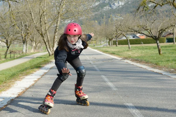 Pretty preteen girl on roller skates in helmet at a track