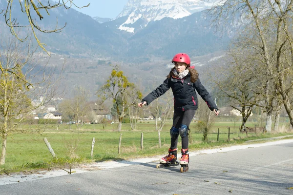 Pretty preteen girl on roller skates in helmet at a track