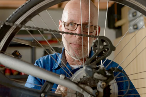 Man repairing bike gear in his workshop.