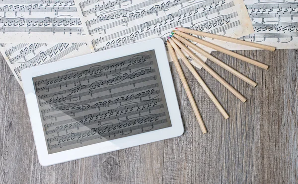 Musical scores with a digital tablet placed on an ancient table