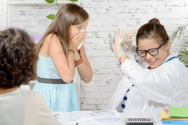 A girl sneezing in the doctor\'s office