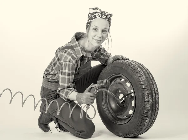 Black and white vintage and young woman inflates a car tire