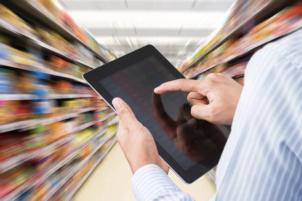 Businessman checking inventory in supermarket on touchscreen tablet