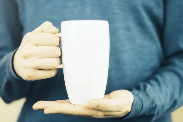 Hands holding a tall white coffee mug