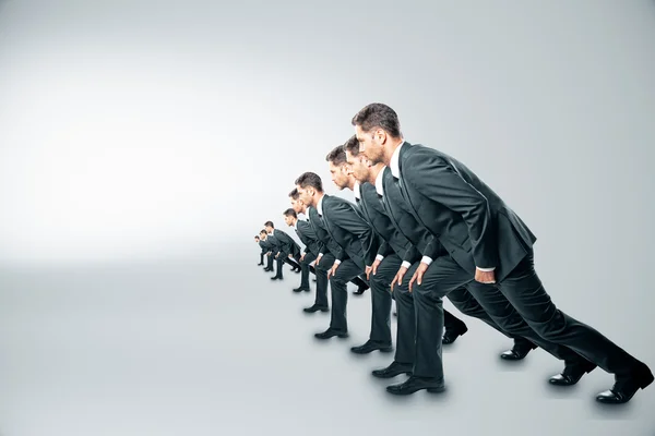 Competition concept with businessmen about to run on grey background