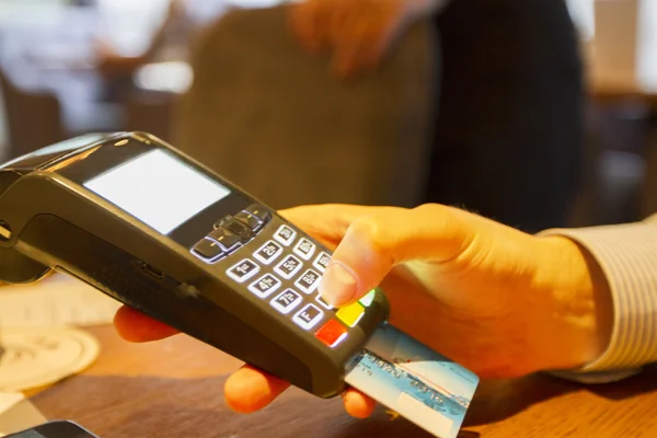 Hand with credit card swipe through terminal