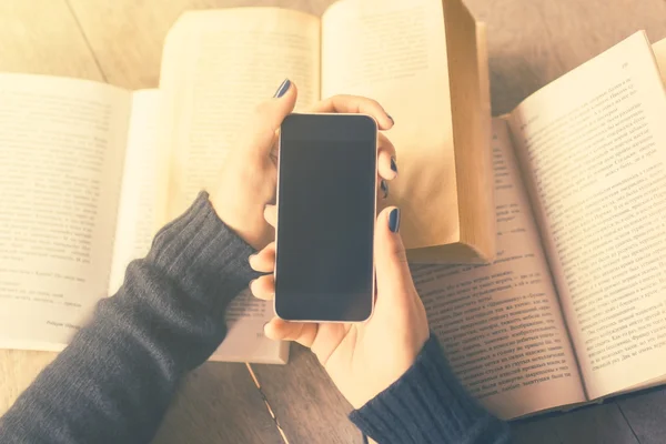 Girl with blank cell phone and books